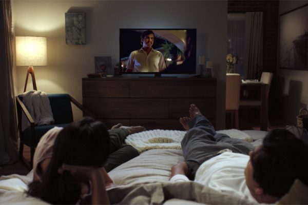 Photo of two poeple on a bed wathing a TV courtesy of Netflix